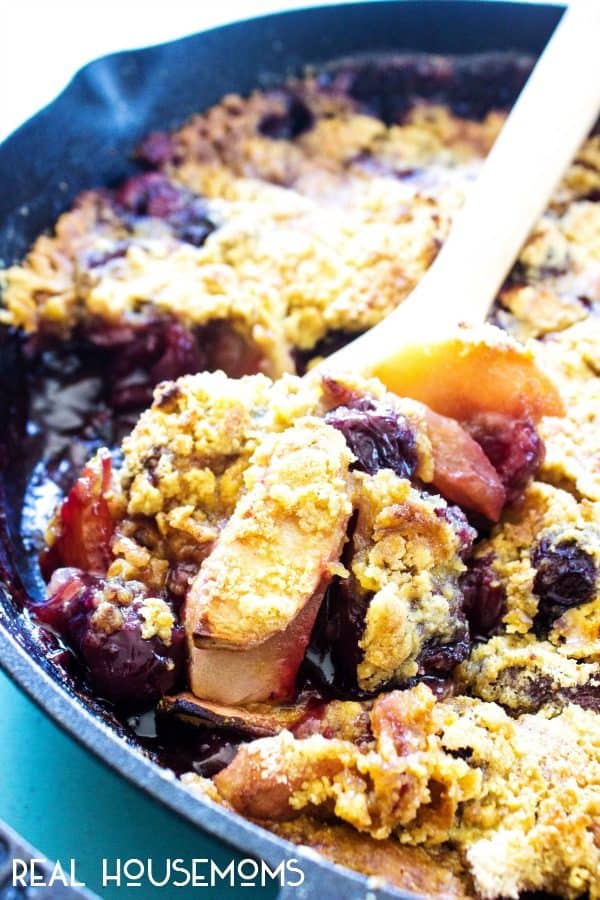 Apple Cherry Cobbler being scooped out of a cast iron skillet for serving