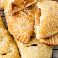 air fryer apple hand pies piled up on a wire rack with one pie broken open with recipe name at the bottom