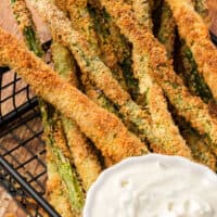 close up of air fryer asparagus fries in a wire basket with recipe name at the bottom