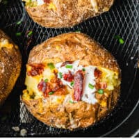 loaded air fryer backed potatoes in an air fryer basket with recipe name at the bottom