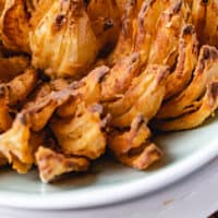 air fryer blooming onion in a bowl with recipe name at the bottom