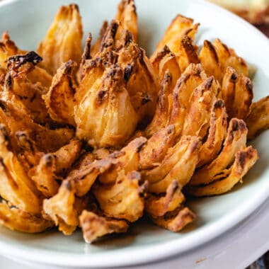 square image of a crispy air fryer blooming onion in a serving bowl