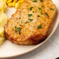 air fryer boneless pork chop on a plate with side dishes with recipe name at the bottom