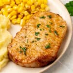 air fryer boneless pork chop topped with parsley on a dinner plate with side dishes