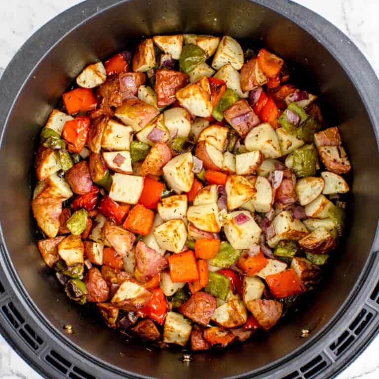 square image of cooked air fryer breakfast potatoes in the air fryer basket