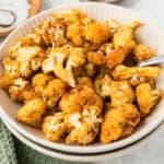 square image of air fryer cauliflower in a serving bowl with a spoon