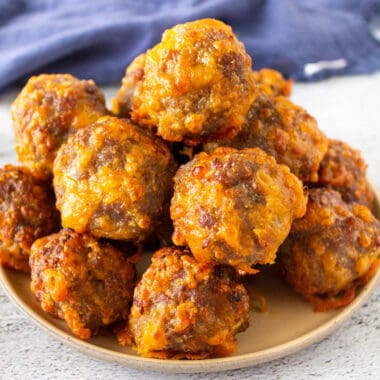 square image of air fryer cheddar & sausage balls piled on a plate