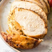 slice air fryer chicken breast on a plate with salad with recipe name at the bottom