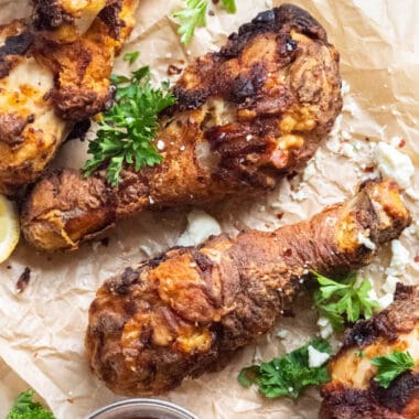 square image of two air fryer chicken legs on parchment paper