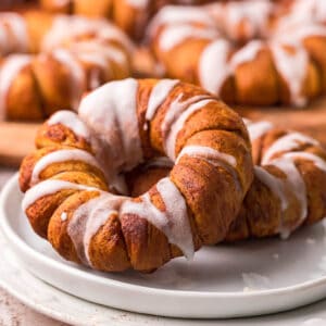 square image of two air fryer cinnamon roll wrapped apple rings on a small plate