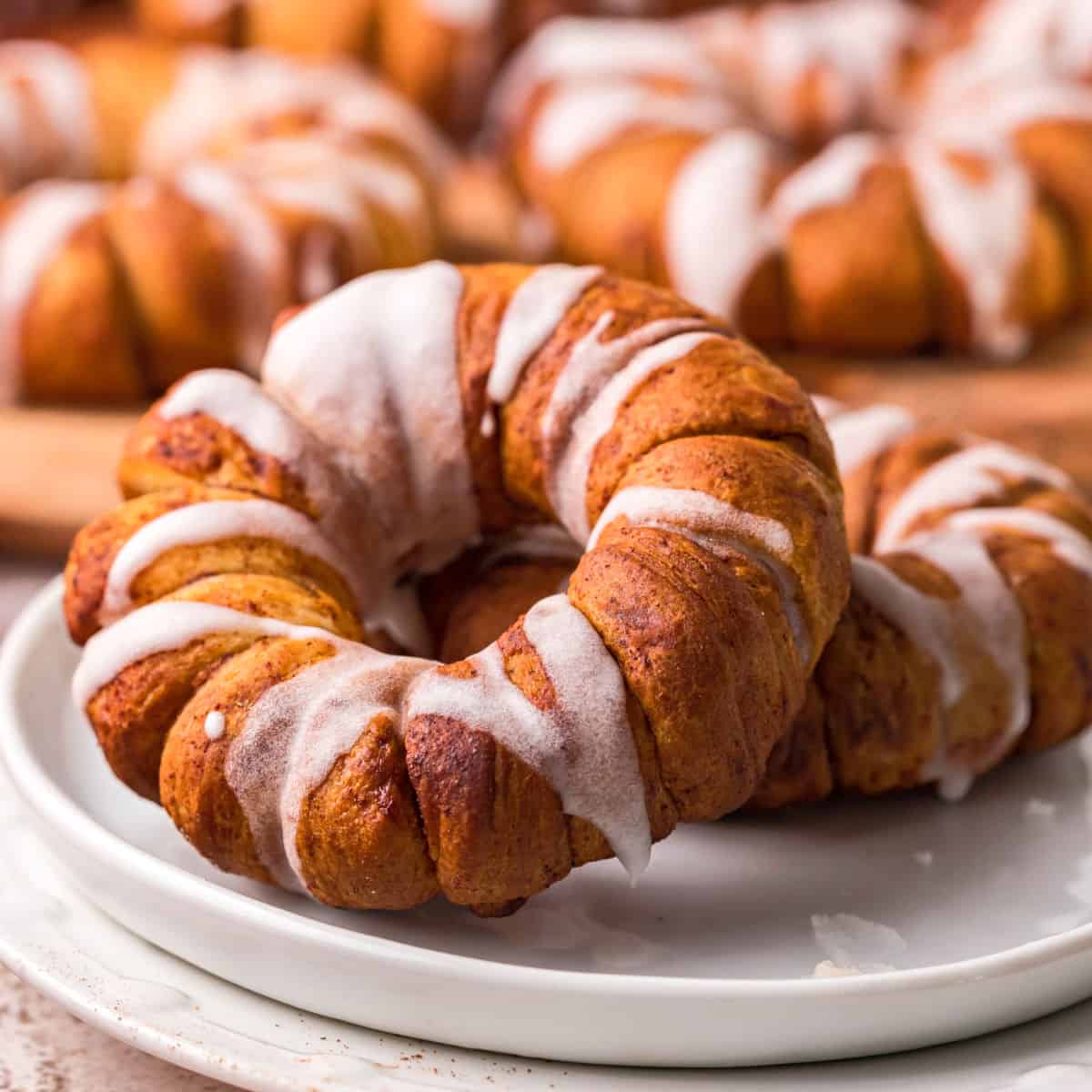 square image of two air fryer cinnamon roll wrapped apple rings on a small plate