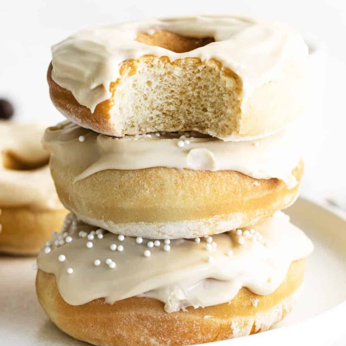 square image of air fryer coffee donuts stacked up with a bite taken out of the top donut