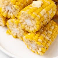 air fryer corn on the cob ears cut in half and piled on a platter with recipe name at the bottom