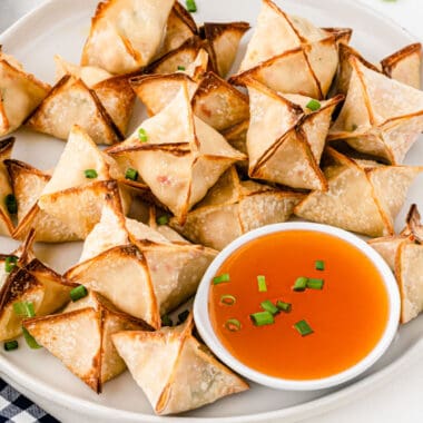square image of air fryer crab rangoon on a plate with a bowl of duck sauce