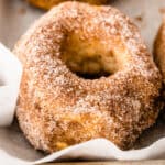 square close up image of a cinnamon-sugar air fryer donut on a baking sheet with parchment paper