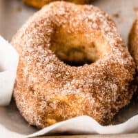 square close up image of a cinnamon-sugar air fryer donut on a baking sheet with parchment paper