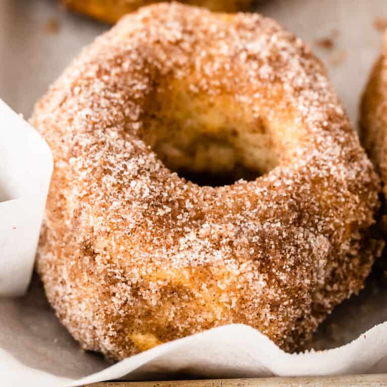 square close up image of a cinnamon-sugar air fryer donut on a baking sheet with parchment paper