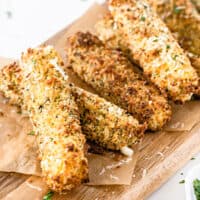 square image of air fryer mozzarella sticks on a cutting board with parchment paper