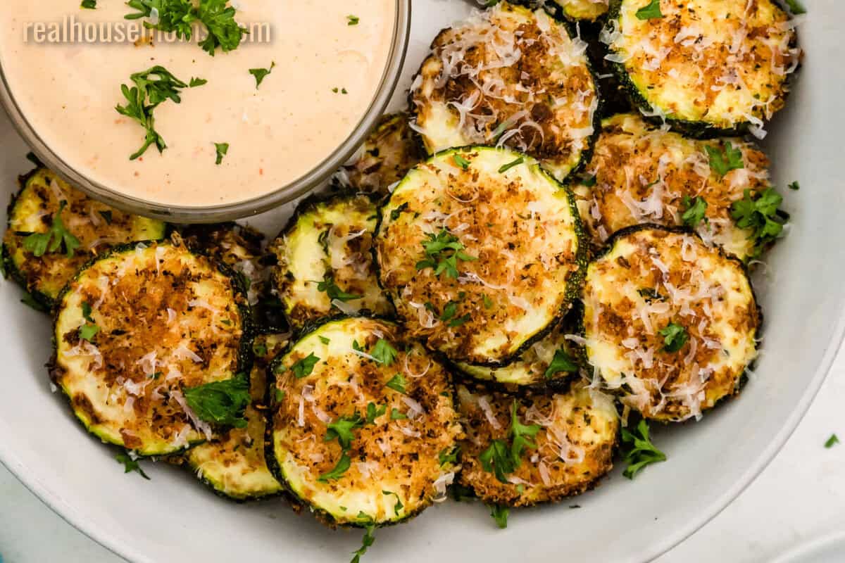 looking down at a bowl of Air Fryer Parmesan Zucchini with a small bowl of dipping sauce
