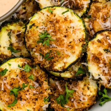 square close up of air fryer parmesan zucchini slices piled on a plate