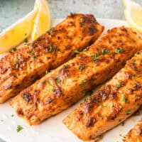 square image of air fryer salmon filets topped with chopped parsley on a platter