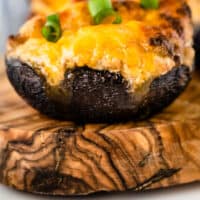 close up of an air fryer stuffed mushroom on a wooden board with recipe name at the bottom