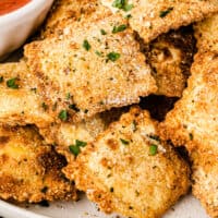 air fryer toasted ravioli piled up on a plate with recipe name at the bottom
