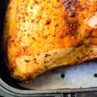 turkey breast with golden brown skin in an air fryer with recipe name at the bottom