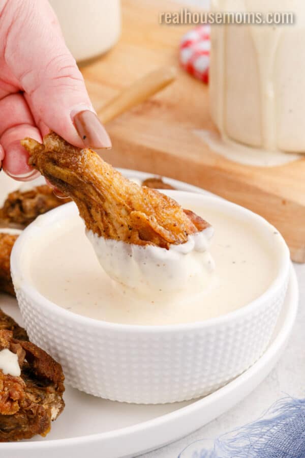 chicken wing being dipped in alabama white sauce