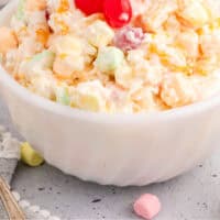 ambrosia salad topped with cherries with recipe name at the bottom