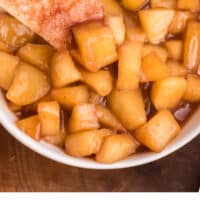 cinnamon sugar tortilla chips in a bowl of apple pie dip with recipe name at the bottom