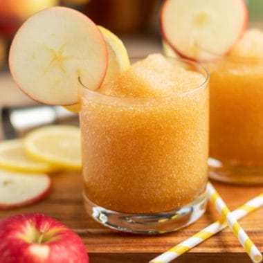 apple whiekey sour slush in a glass with an apple slice for garnish