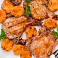 apricot grilled pork chops on a platted with apricots with recipe name at the bottom