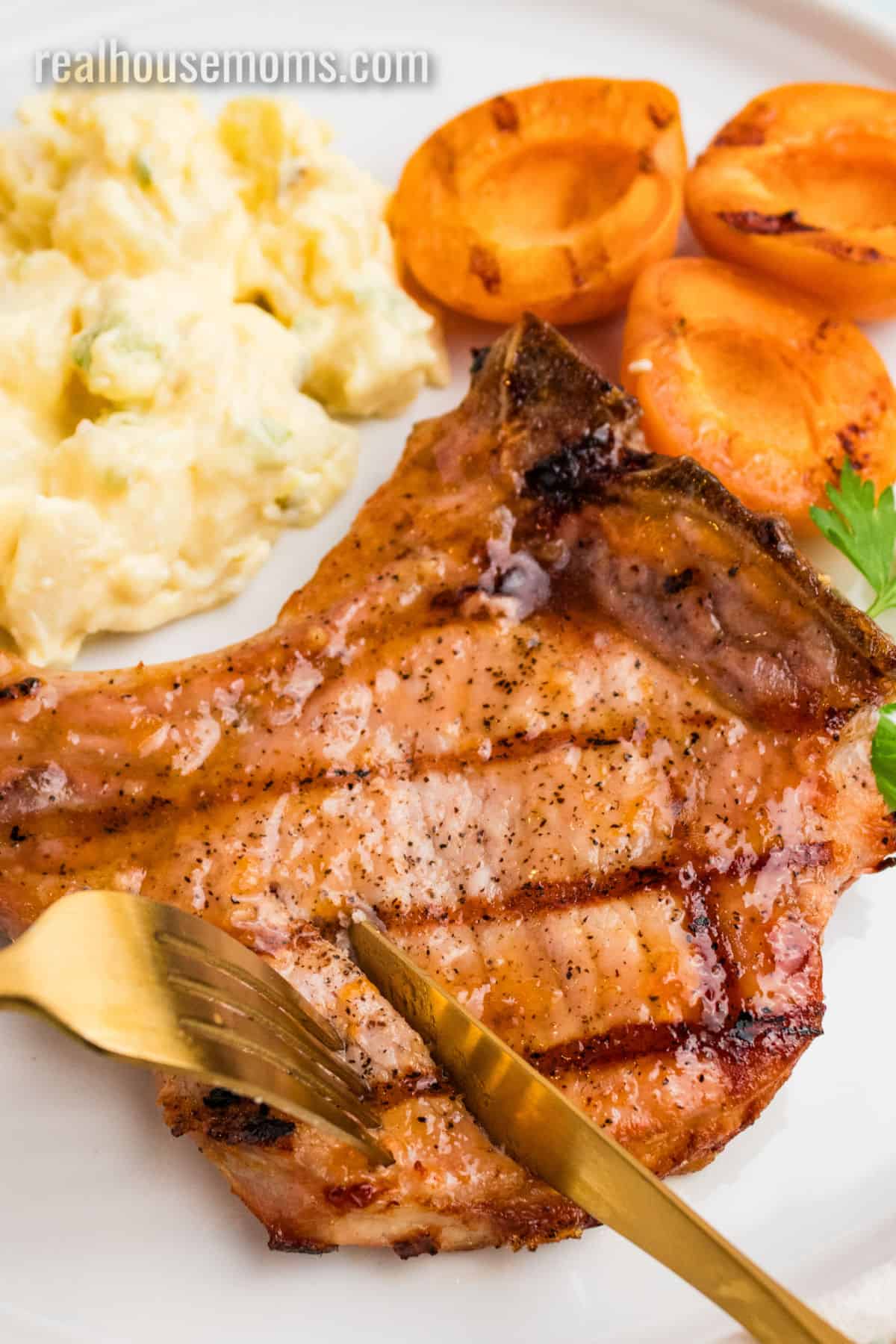 fork and knife cutting into a apricot grilled pork chop