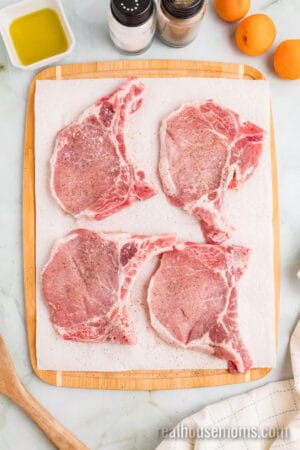 bone-in pork chops on paper towels on a cutting board