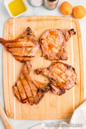 cooked apricot grilled pork chops on a cutting board after resting