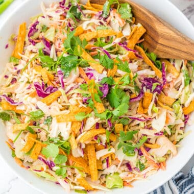 square image of asian slaw in a bowl with cilantro and crunch y noodles on top