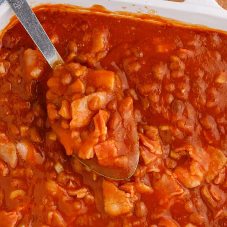 square image of bbq baked beans on a spoon over the dish