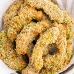 square image of avocado fries in a basket with paper towels