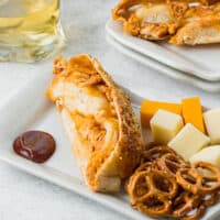 slices of bbq chicken stuffed bread on plate with cheese and pretzels with recipe name at the bottom