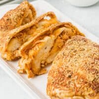 square image of a loaf of bbq chicken stuffed bread cut into slices on a platter