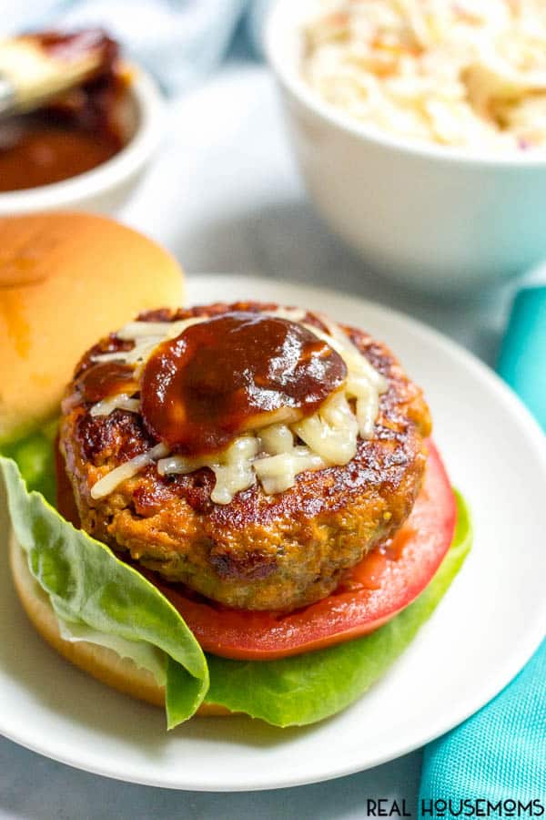 BBQ Chicken Burger cooked and on a bun with lettuce, tomato, cheese, and BBQ sauce.