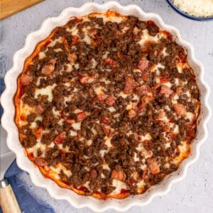 square image of a bacon & bison low carb pizza in the dish