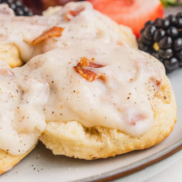 square close up image of bacon gravy served over homemade biscuits