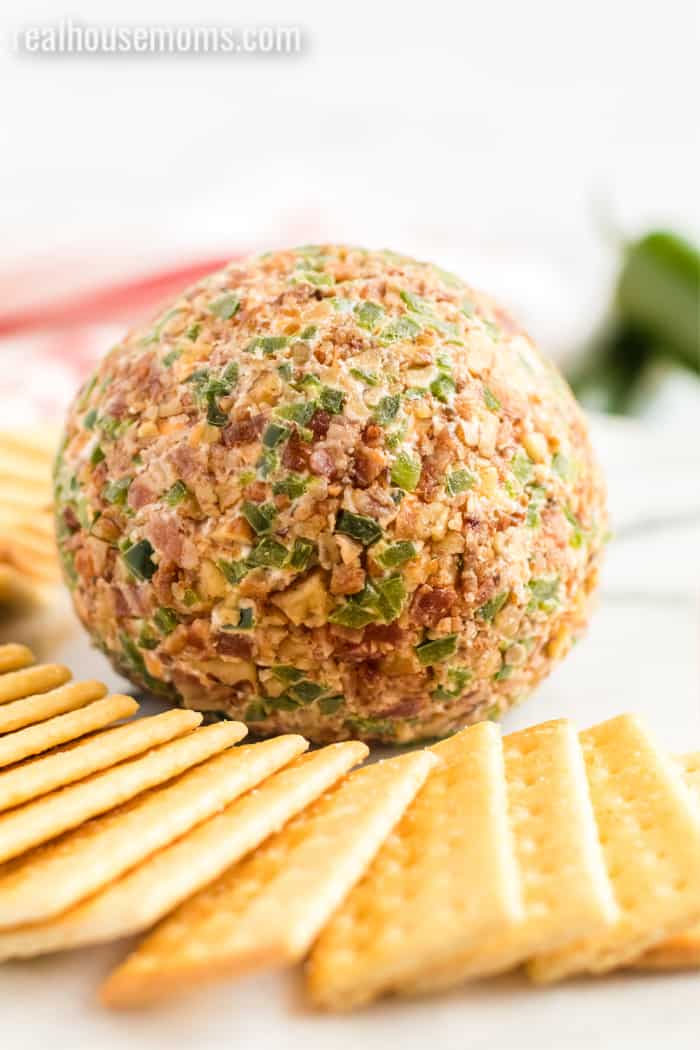 bacon jalapeno cheese ball on a plate surrounded by crackers