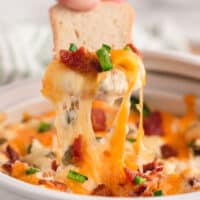 square image of bacon jalapeno popper dip on a cracker with melty cheese above the bowl