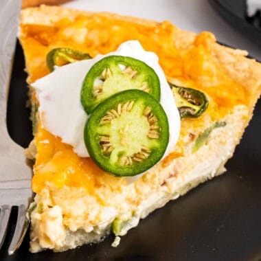 square image of a slice of bacon jalapeno popper quiche on a black plate