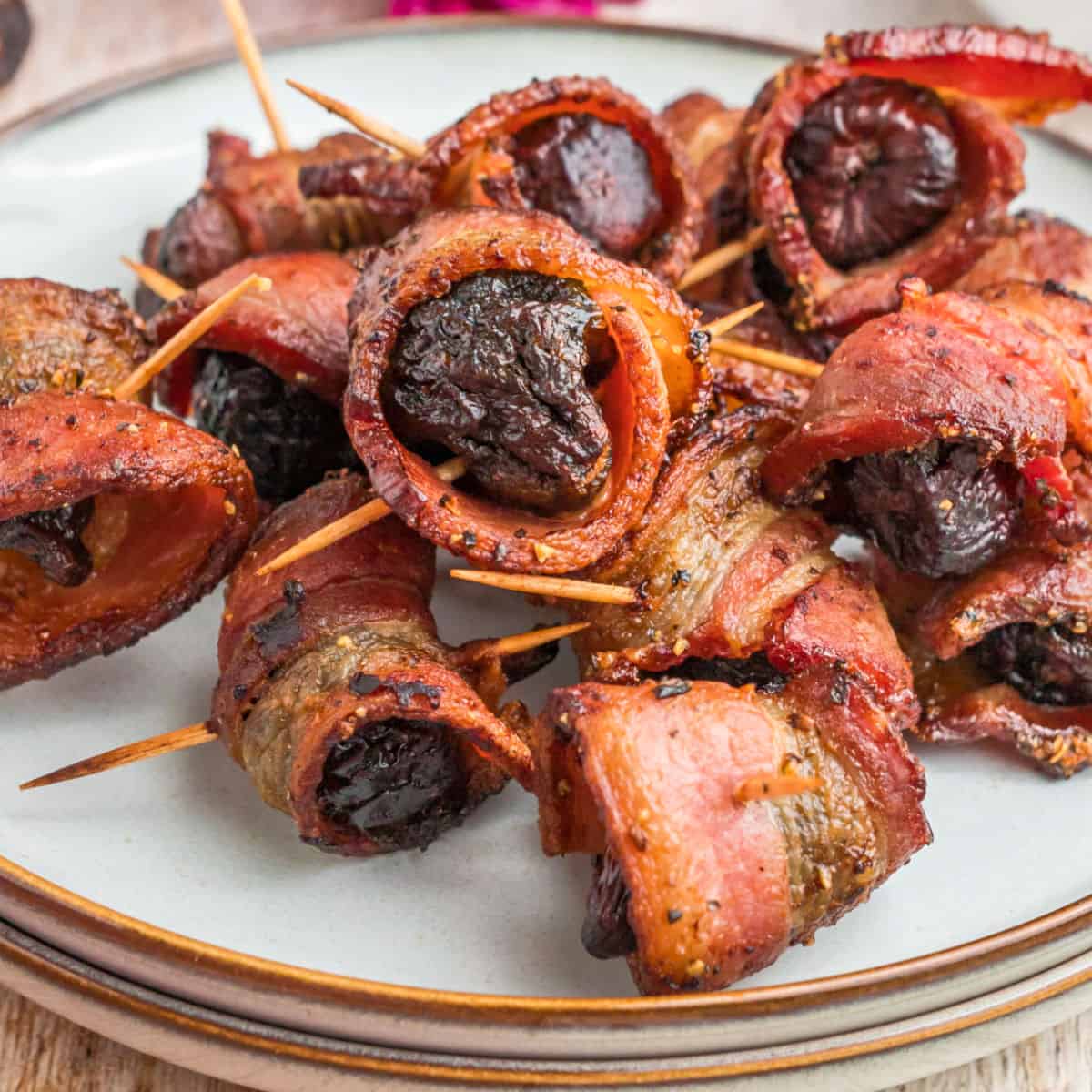square close up image of bacon wrapped figs on a plate