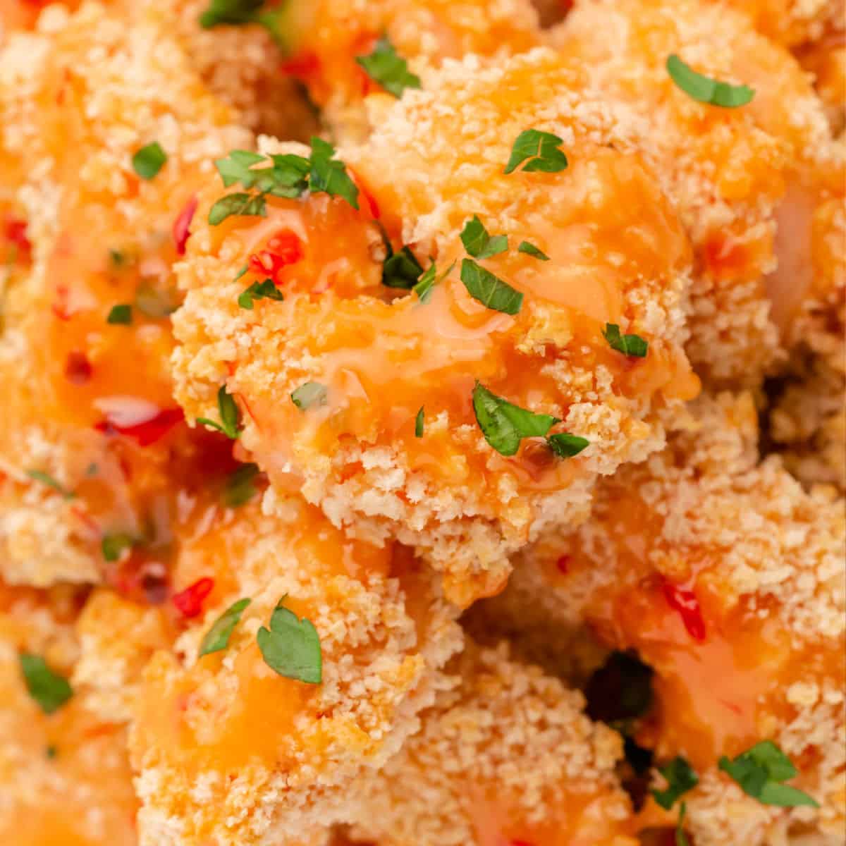 square image of bang bang shrimp piled on a plate with extra sauce spooned over the top