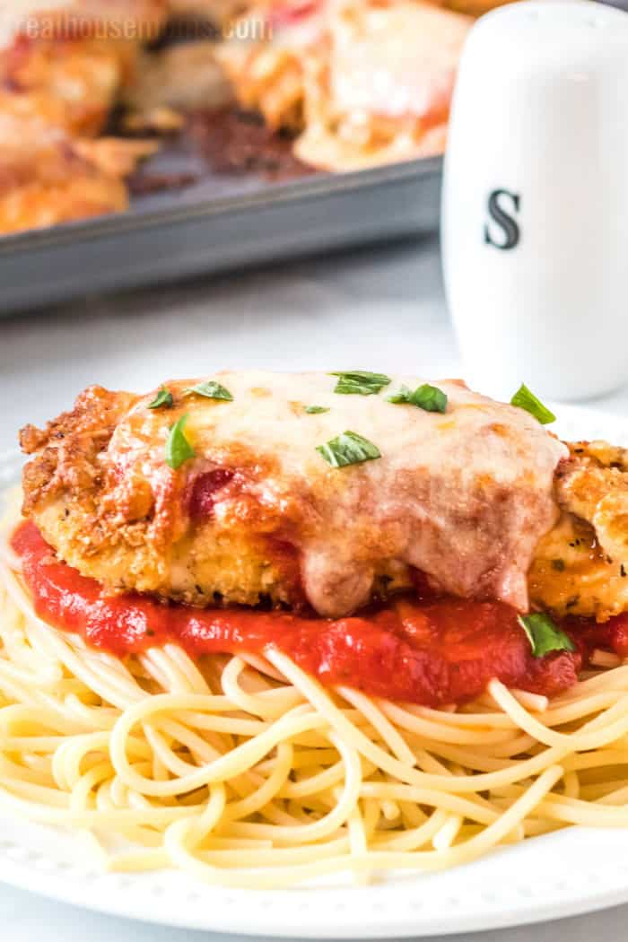 baked chicken parmesan over a bed of spaghetti